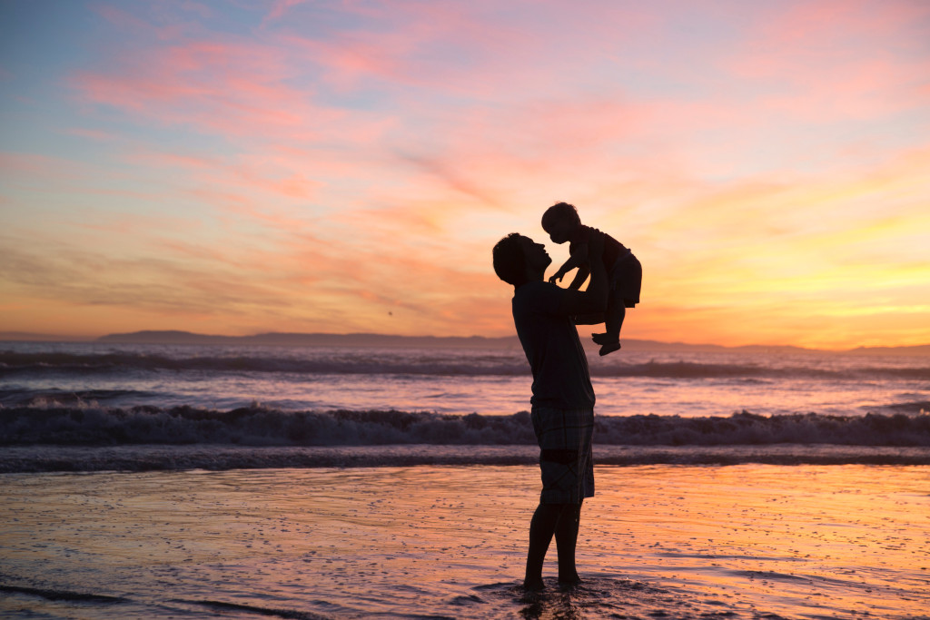 Padre alzando a su hijo en la playa frases para padres fallecidos