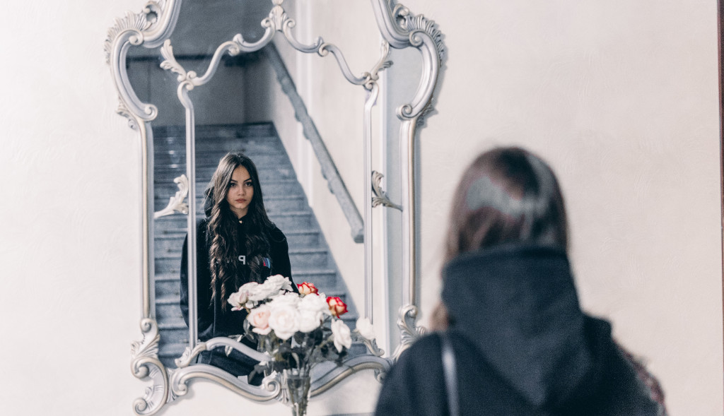 mujer frente a un espejo y rosas